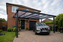Anthracite grey PolycarbonateX carport with bronze 25mm multiwall polycarbonate sheets installed on a detached British family home.