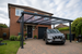Anthracite grey PolycarbonateX carport with bronze 25mm multiwall polycarbonate sheets installed on a detached British family home.